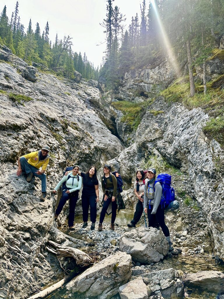 small group of people outdoors with rock and tree backdrop
